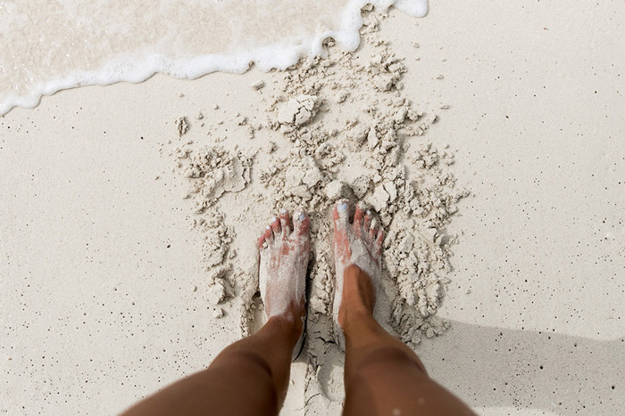 Women on beach with foot in the sand